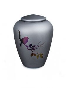 Glazen urn met een vogeltje op een tak - symbool van troost en vrijheid